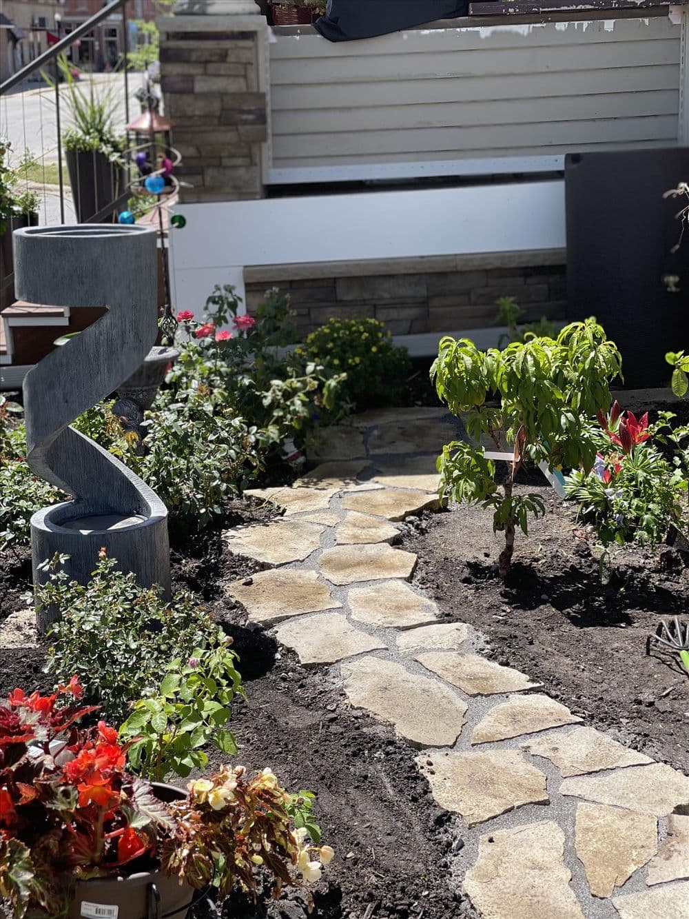 Garden path winding through vibrant flower beds with decorative stone and a unique fountain.