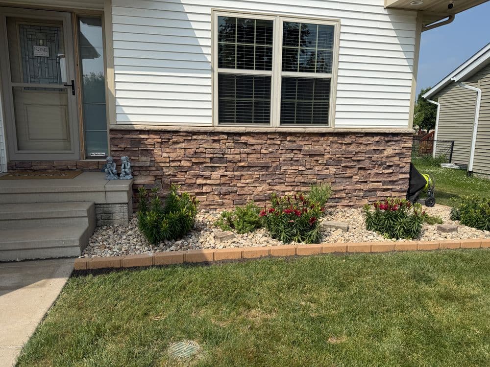 House exterior with stone accent wall, landscaped garden featuring flowers and decorative stones.