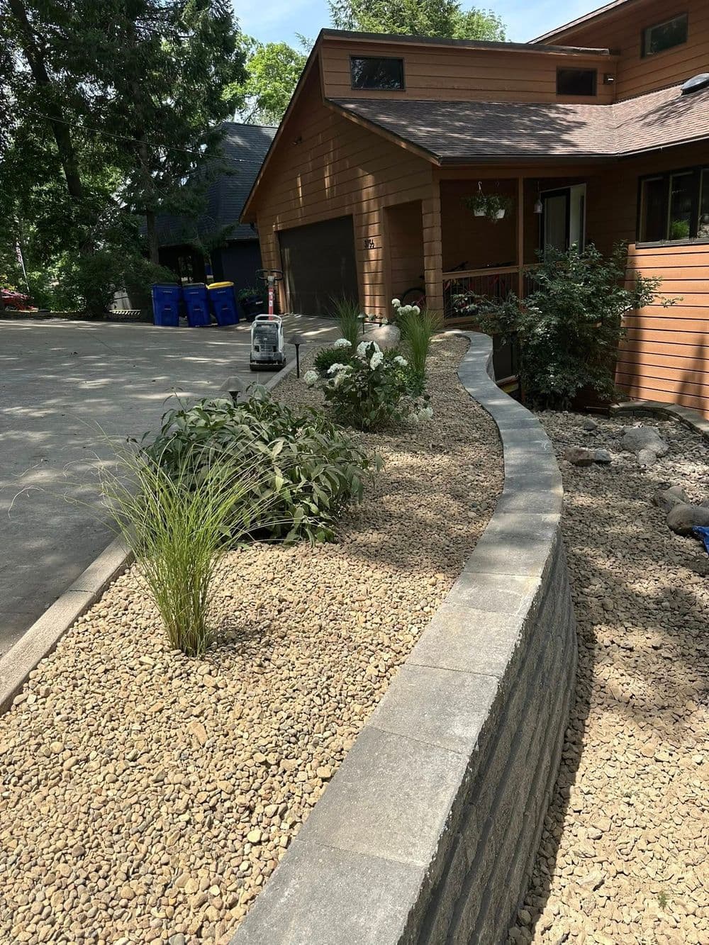 Landscaped garden with decorative stones, plants, and modern home exterior on a sunny day.