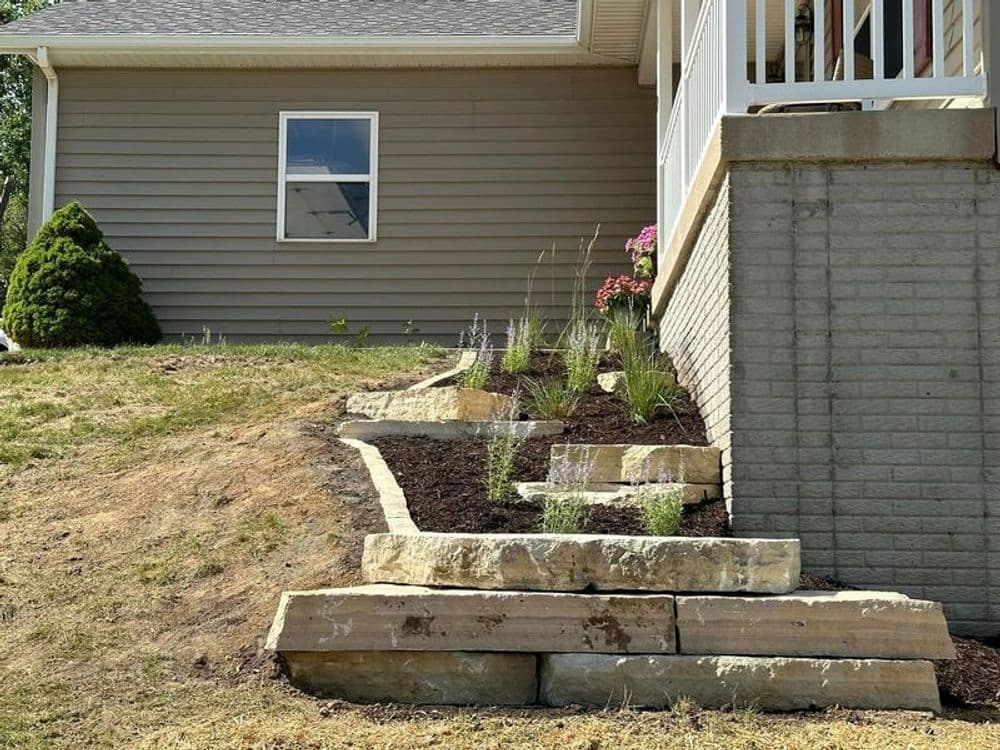 Stone steps leading to a house, featuring landscaped garden with plants and flowers.