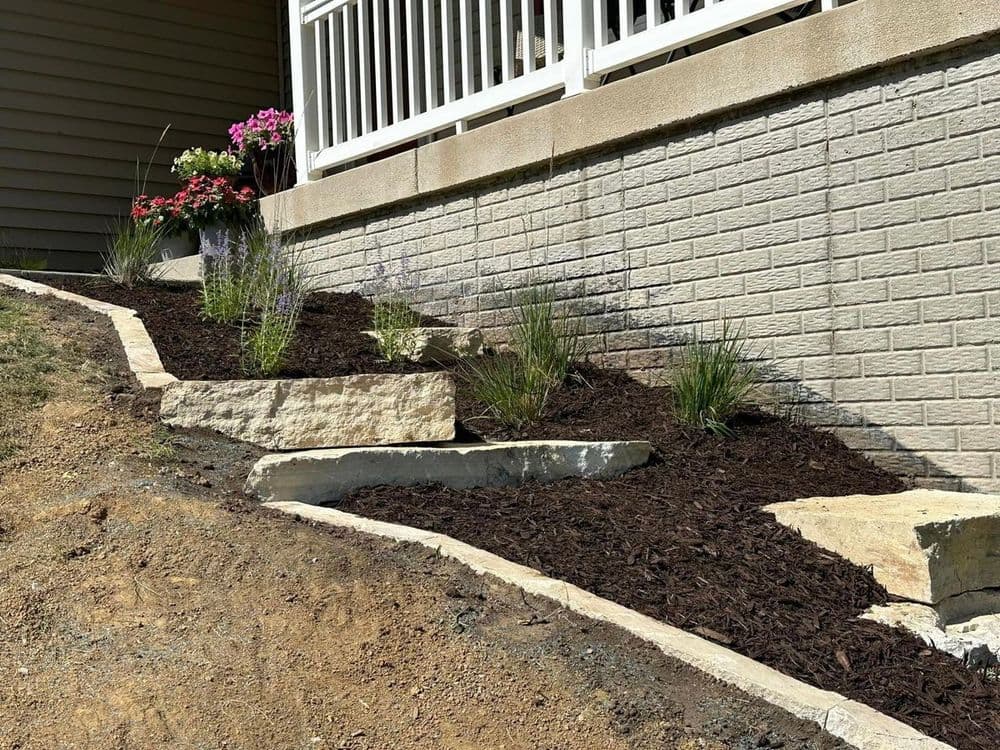Landscape design featuring stone steps, mulch, and ornamental plants on a sloped yard.