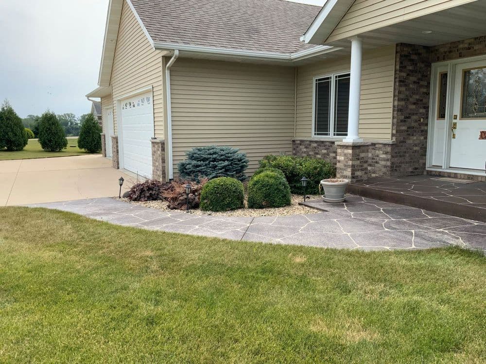 Landscaped front yard with shrubs, stones, and a home exterior featured in a suburban setting.